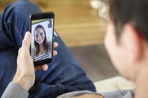 Videokontakt på mobiltelefon Ung mann har videokontakt med sin venninne